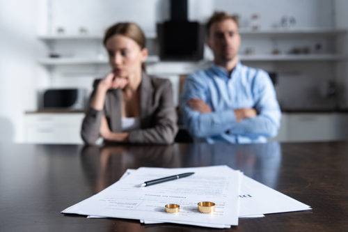 couple getting divorce papers and close up on papers with rings on top