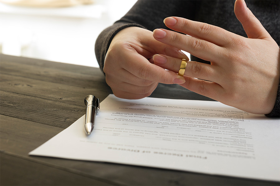person removing wedding ring signing papers