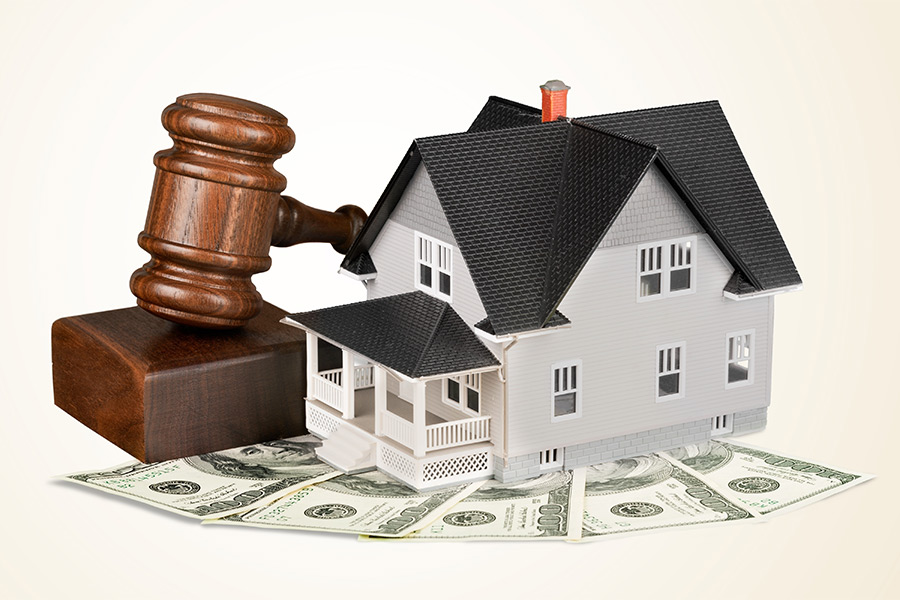 small house model with gavel on top of money